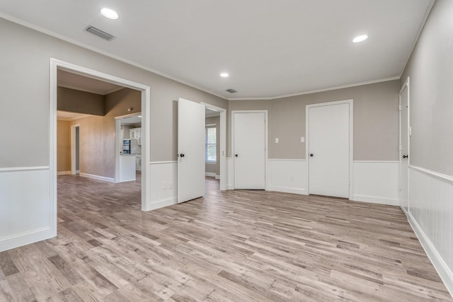 spare room featuring crown molding and light wood-type flooring