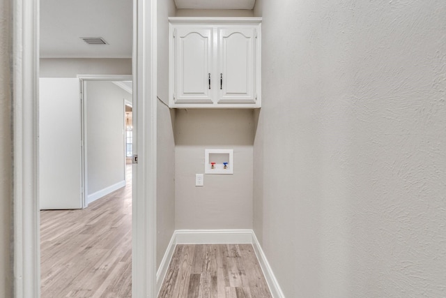 laundry room with washer hookup, light hardwood / wood-style flooring, and cabinets