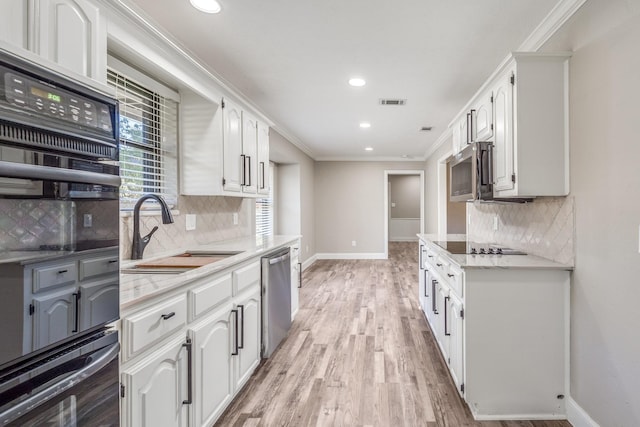 kitchen featuring sink, white cabinets, backsplash, ornamental molding, and black appliances