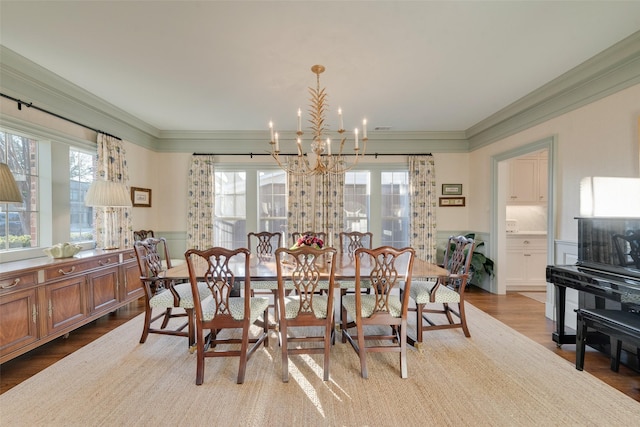 dining space with a notable chandelier, ornamental molding, and light wood-type flooring