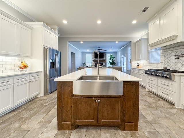 kitchen featuring decorative backsplash, a center island with sink, and appliances with stainless steel finishes