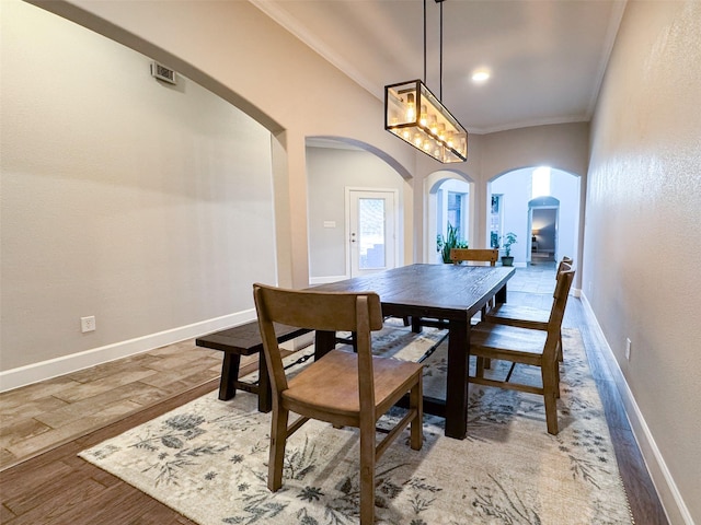 dining space with wood-type flooring and ornamental molding