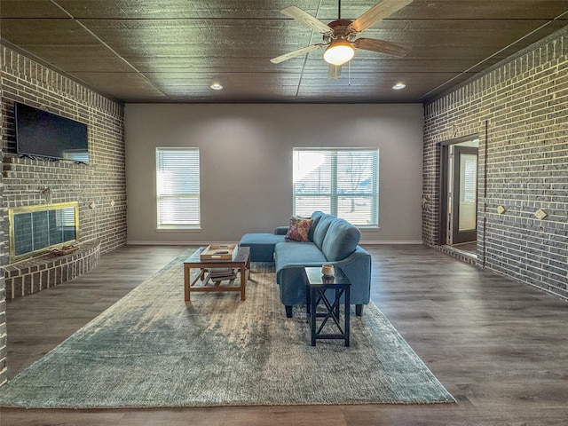 living room featuring wood ceiling, wood-type flooring, ceiling fan, brick wall, and a fireplace