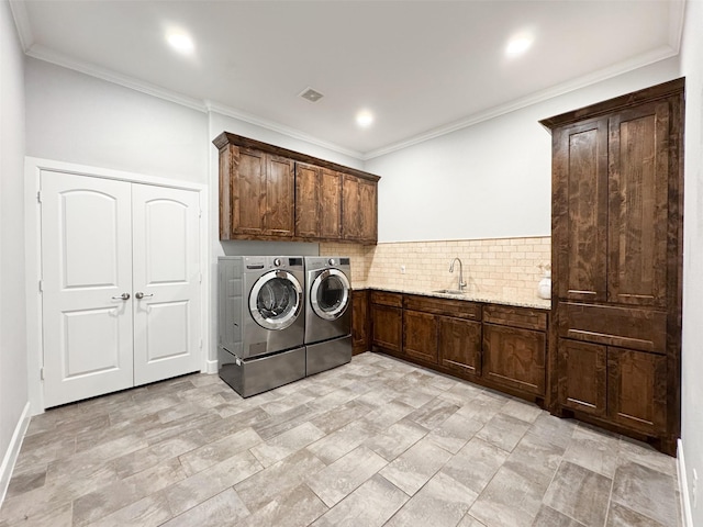 clothes washing area with cabinets, independent washer and dryer, crown molding, and sink