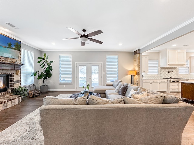 living room with hardwood / wood-style flooring, crown molding, a fireplace, and french doors