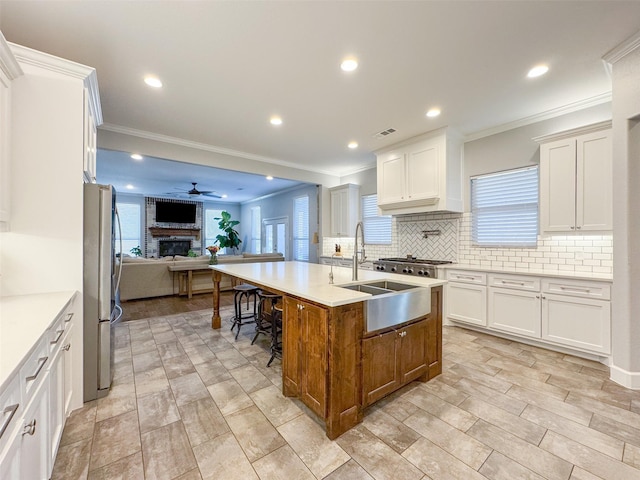 kitchen featuring appliances with stainless steel finishes, a kitchen bar, an island with sink, and white cabinets