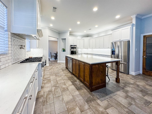 kitchen featuring a breakfast bar, white cabinetry, tasteful backsplash, appliances with stainless steel finishes, and a kitchen island