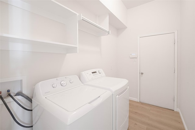 clothes washing area featuring washing machine and dryer and light hardwood / wood-style flooring