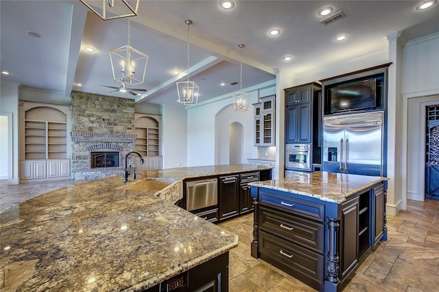 kitchen with built in shelves, sink, hanging light fixtures, stainless steel appliances, and a large island