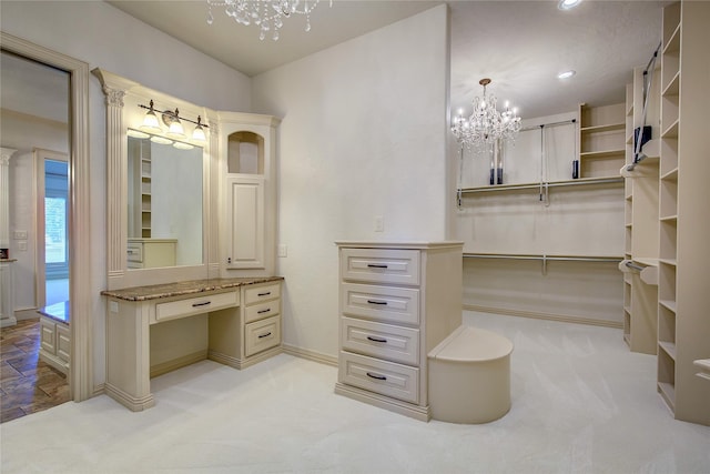 walk in closet featuring built in desk, light colored carpet, and an inviting chandelier