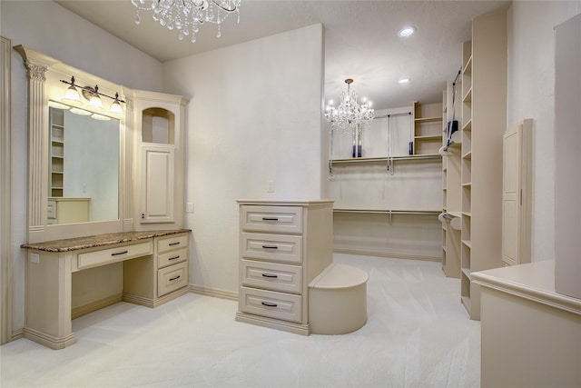 walk in closet featuring built in desk, light carpet, and a chandelier