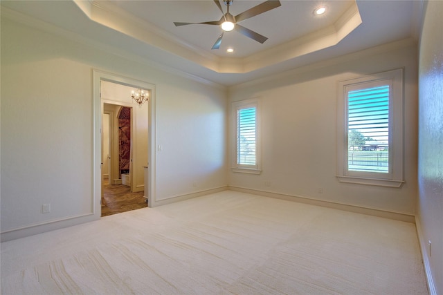 unfurnished bedroom featuring ceiling fan, ornamental molding, a tray ceiling, and light carpet