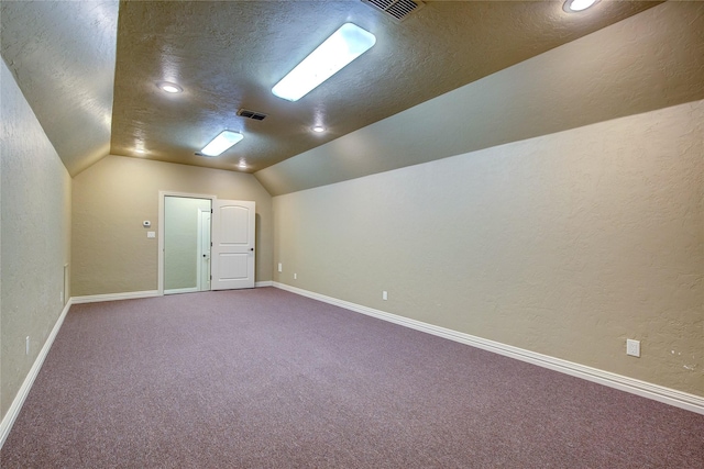 additional living space featuring vaulted ceiling, carpet, and a textured ceiling