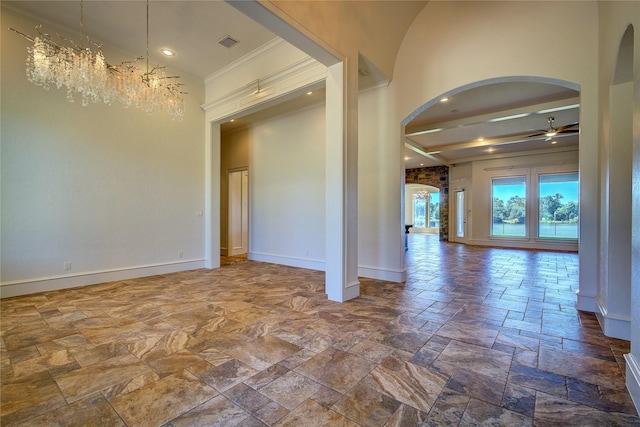 unfurnished room featuring a towering ceiling, ceiling fan with notable chandelier, and ornamental molding