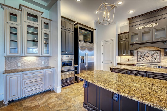 kitchen with tasteful backsplash, crown molding, stainless steel appliances, and decorative light fixtures