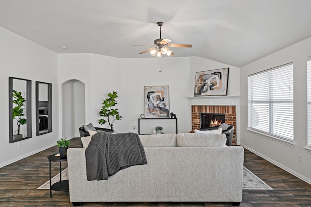 living room with a brick fireplace, dark hardwood / wood-style floors, and ceiling fan