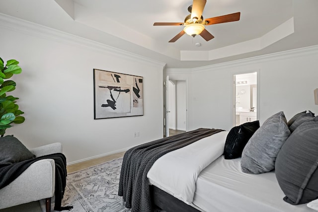 bedroom with connected bathroom, crown molding, a raised ceiling, and ceiling fan