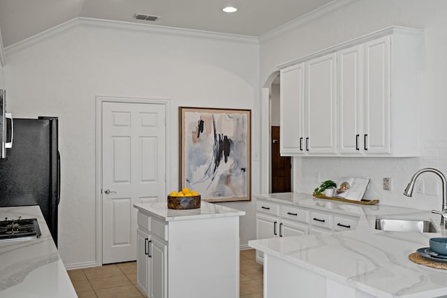 kitchen featuring sink, white cabinetry, a kitchen island, light stone countertops, and light tile patterned flooring