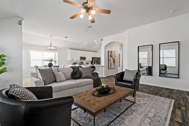 living room with wood-type flooring, lofted ceiling, and ceiling fan with notable chandelier