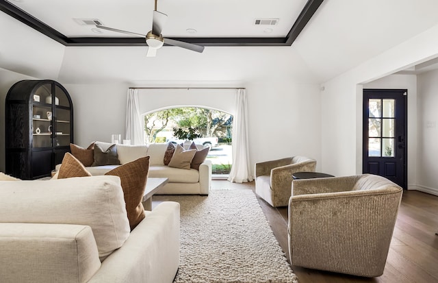 living room featuring dark wood-type flooring, a raised ceiling, and ceiling fan