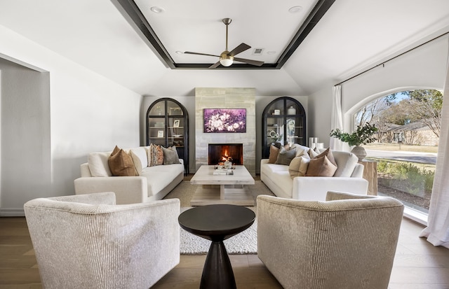 living room with lofted ceiling, a fireplace, ceiling fan, and visible vents