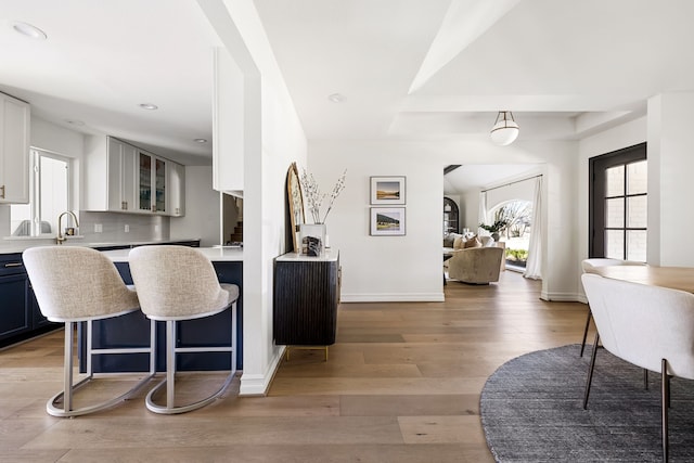 kitchen with tasteful backsplash, light hardwood / wood-style floors, a breakfast bar, and white cabinets