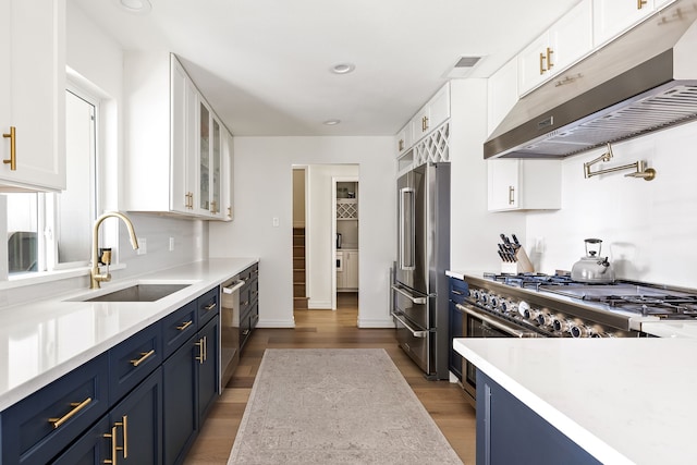 kitchen with glass insert cabinets, white cabinets, a sink, and under cabinet range hood