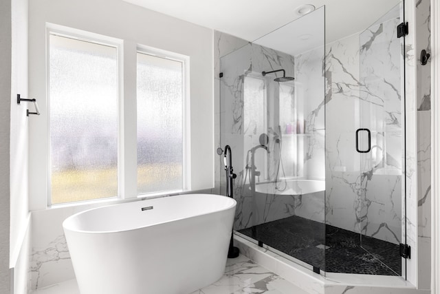 full bathroom featuring marble finish floor, a freestanding tub, and a marble finish shower