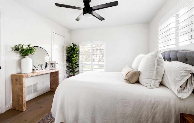 bedroom featuring baseboards, ceiling fan, visible vents, and wood finished floors