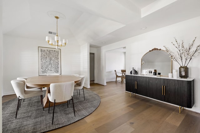 dining room featuring an inviting chandelier, baseboards, visible vents, and wood finished floors