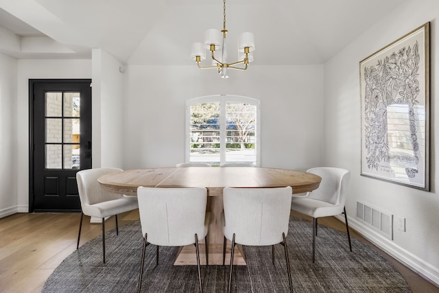 dining room with a wealth of natural light, visible vents, a notable chandelier, and wood finished floors