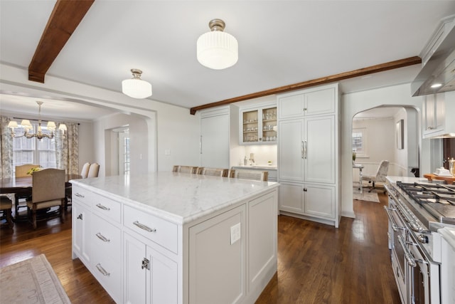 kitchen with white cabinets, dark hardwood / wood-style flooring, hanging light fixtures, a center island, and light stone countertops