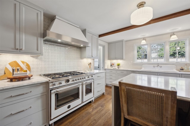 kitchen featuring pendant lighting, gray cabinetry, tasteful backsplash, custom range hood, and range with two ovens