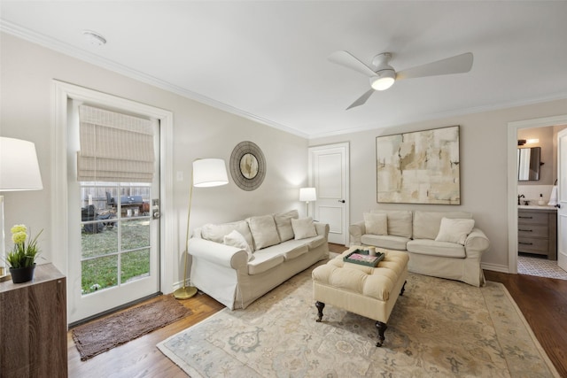 living room featuring wood-type flooring, ornamental molding, and ceiling fan