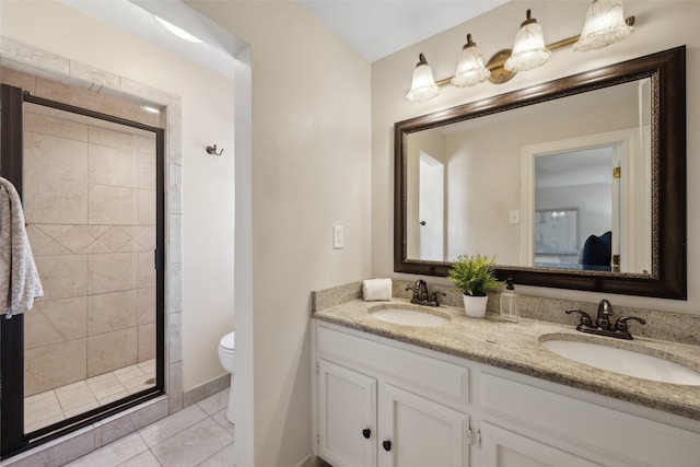 bathroom featuring tile patterned flooring, vanity, toilet, and a shower with shower door