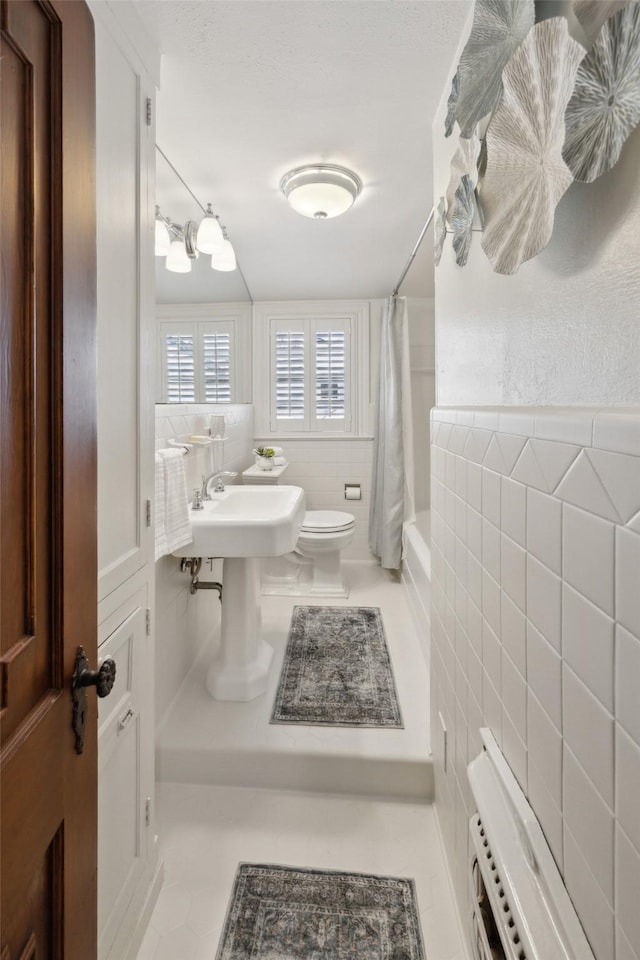 bathroom with tile walls, tile patterned floors, toilet, and shower / tub combo with curtain