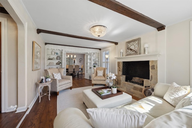 living room featuring built in shelves, crown molding, dark hardwood / wood-style flooring, a notable chandelier, and a fireplace