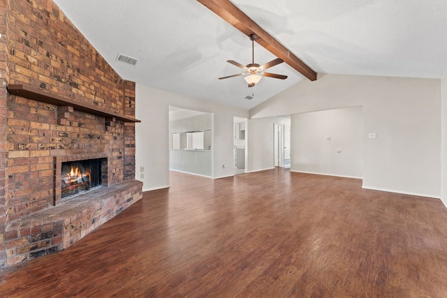 unfurnished living room featuring dark wood-type flooring, ceiling fan, a fireplace, lofted ceiling with beams, and a textured ceiling