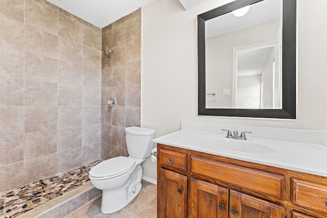 bathroom with tiled shower, vanity, and toilet