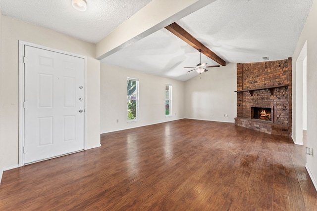 unfurnished living room featuring ceiling fan, dark hardwood / wood-style floors, a fireplace, lofted ceiling with beams, and a textured ceiling