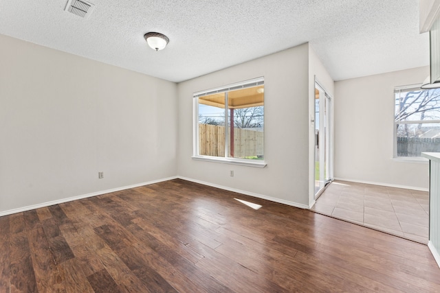 spare room with a healthy amount of sunlight, hardwood / wood-style floors, and a textured ceiling