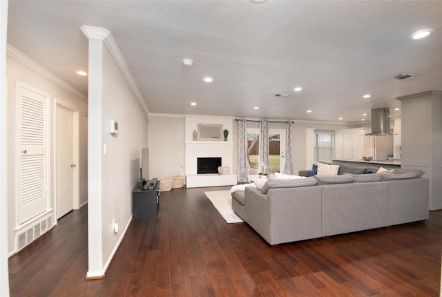 living room with crown molding, a large fireplace, and dark hardwood / wood-style flooring