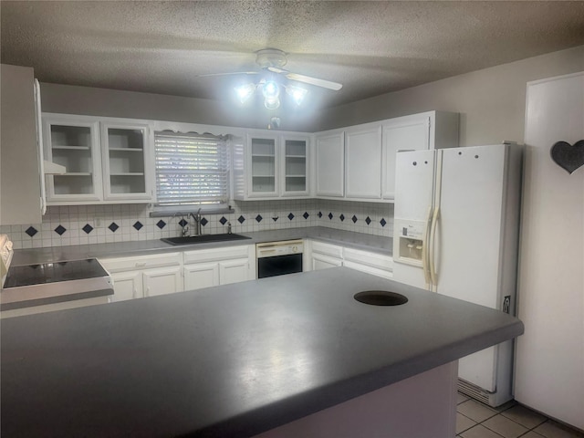 kitchen featuring light tile patterned flooring, sink, white cabinets, dishwashing machine, and a textured ceiling