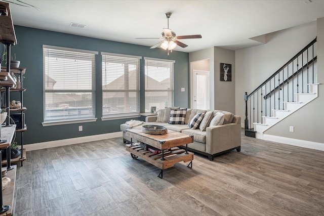 living room with stairway, wood finished floors, visible vents, and baseboards