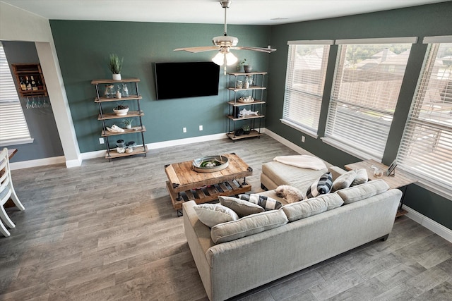 living area with a ceiling fan, baseboards, and wood finished floors