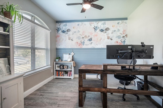 office area with a wainscoted wall, wood finished floors, a ceiling fan, and baseboards