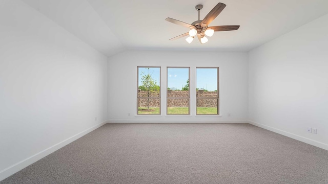 carpeted empty room with a ceiling fan, baseboards, and vaulted ceiling