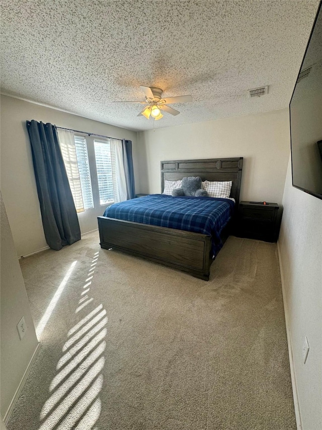 carpeted bedroom featuring ceiling fan and a textured ceiling