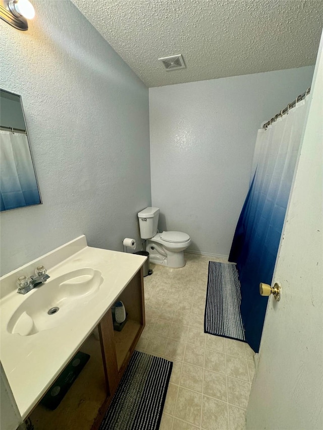 bathroom featuring tile patterned floors, toilet, a textured ceiling, and vanity