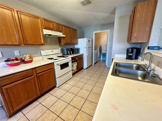 kitchen with sink, separate washer and dryer, a textured ceiling, light tile patterned floors, and white appliances